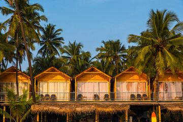 Tropical beach huts with palm trees in the background