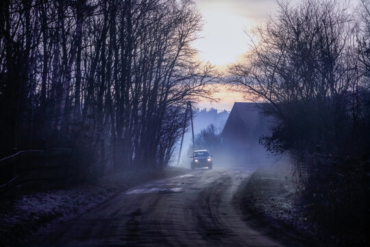 A local, countryside road through a village in the middle of the forest in moody winter evening scenery.