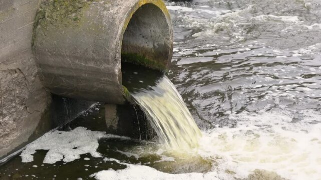 Dirty water flows from the pipe into the river, environmental pollution. Sewerage, treatment facilities
