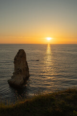 Fototapeta premium The sunset behind Raouche Rock in Lebanon, casting a stunning glow over the Mediterranean waters. Travel blogs, postcards, and tourism advertisements, social media content.