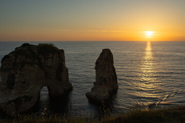 The sunset behind Raouche Rock in Lebanon, casting a stunning glow over the Mediterranean waters....