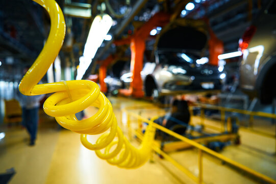 Yellow plastic compressed air hose for working pneumatic tools. Assembly line of an automobile plant.