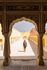 Young blonde woman walking in the courtyard of Hawa Mahal palace in Jaipur, India. European tourist discovering Rajasthani architecture on hot sunny day
