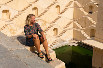 European female traveler sitting on the stairs of stepwell of Jaipur, Rajasthan, India