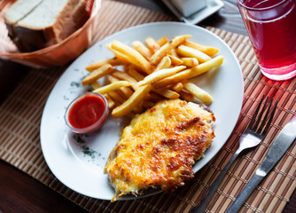 Roasted pork chop with melted cheese, served with french fries and tomato sauce. Popular russian dish French style meat