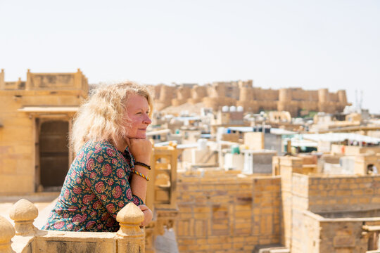 Young blonde European woman travelling in Rajasthan, enjoying panoramic view of Jaisalmer city fort, India