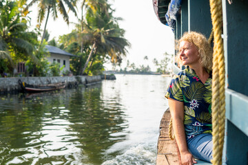 European tourist having a traditional straw houseboat ride on the backwaters of Kerala, India