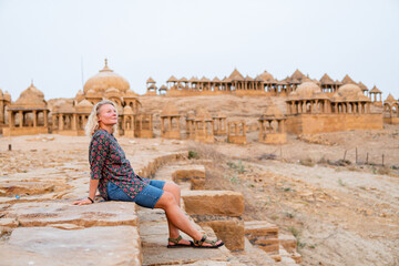 Fototapeta premium Blonde woman exploring historic Bada Bagh tombs made of sandstone in the suburbs of Jaisalmer, Rajasthan, India
