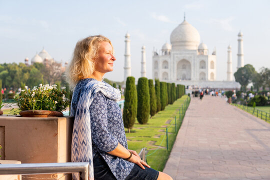 Attractive young woman enjoying the iconic view over the marble white Taj Mahal mausoleum in Agra, Uttar Pradesh, India