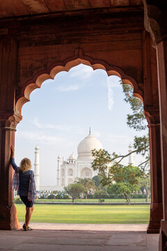 Attractive young woman enjoying the iconic view over the marble white Taj Mahal mausoleum in Agra, Uttar Pradesh, India