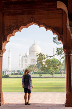 Attractive young woman enjoying the iconic view over the marble white Taj Mahal mausoleum in Agra, Uttar Pradesh, India