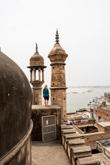 Young woman standing on the mosque roof overlooking Varanasi old town and Ganges river in Uttar...