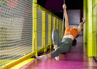 Happy middle-aged woman going down on zipline in adventure park. Rope park indoors
