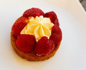Sponge cake with cream and strawberry on white plate