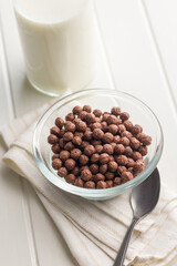 Breakfast cereal chocolate balls in bowl on white table.