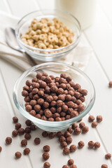 Breakfast cereal chocolate balls in bowl on white table.