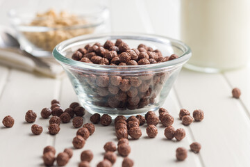 Breakfast cereal chocolate balls in bowl on white table.