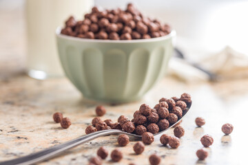 Breakfast cereal chocolate balls on spoon on kitchen table.