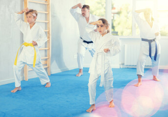 Family with two children in kimono trains karate techniques in studio