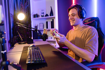Enjoy smart gaming streamer with control joystick, playing game online of live streaming by smartphone rec with team skilled players on computer at modern technology cyber neon light room. Pecuniary.