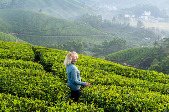 Young blonde woman hiking among tea plantations in Munnar, Kerala, India