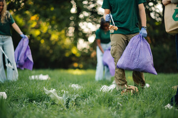 Volunteers picking up trash in the park wearing matching shirts