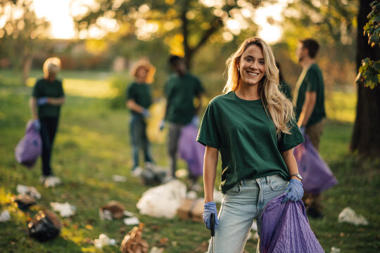 Young woman volunteering collecting trash in public park
