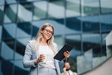 Businesswoman smiling and using digital tablet outdoors