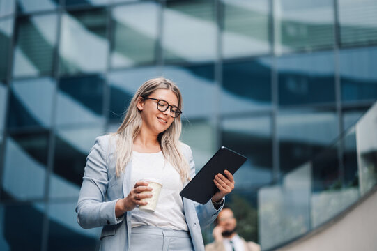 Businesswoman smiling and using digital tablet outdoors - Powered by Adobe