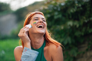 Happy activist painting rainbow flag on face celebrating gay pride
