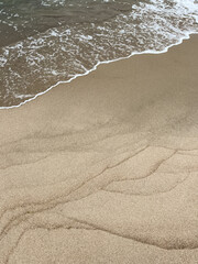 Wet sand with curves and wave of sea. Natural background.