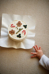 a child dressed in Christmas clothes like a little gnome pokes a Christmas cake with his finger, wants to know what the consistency is, experiments, learns about the world