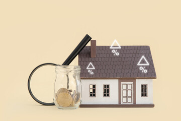 House figure with coins and magnifier on pale yellow background. Concept of buying real estate