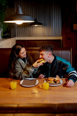 Happy couple enjoying a burger and orange juice together in a cozy burger joint
