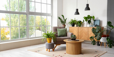 Interior of living room with green plants, table and armchair