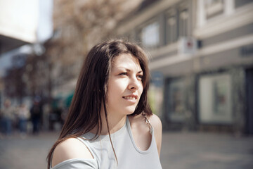 Young woman gazing thoughtfully in a lively urban setting on a sunny day