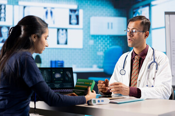 Fototapeta premium Indian male doctor recommending prescription treatment and drugs, explaining the right dosage for wellness and recovery. Medic gives painkillers and vitamins to ill woman at check up.