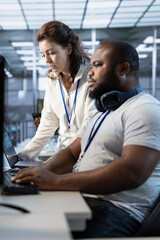 Teamworking colleagues updating AI systems, writing intricate binary code scripts on PC and laptop....