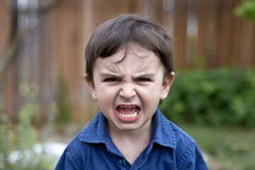 A photo of an angry little boy with his teeth clenched and eyes wide open.