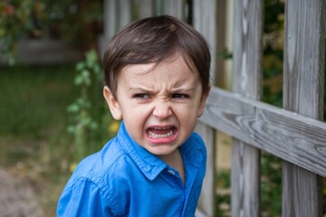 A photo of an angry little boy with his teeth clenched and eyes wide open.