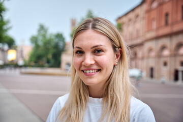 Portrait of Caucasian woman looking at camera and smiling outdoors. Beautiful eastern European girl...