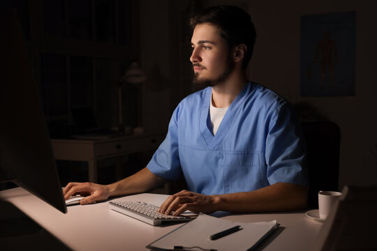 Male nurse with computer working evening shift in clinic