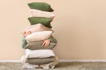Young woman with stack of soft pillows in stylish room