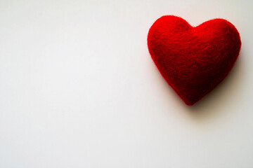 Obraz premium Red felt heart symbolizing love and affection on a plain background
