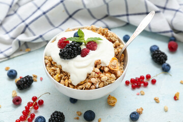 Napkin, bowl of tasty granola with yogurt and berries on pale blue background, closeup