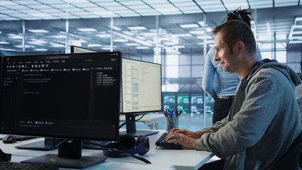 IT technician looking at PC screen, working in network security data center, ensuring optimal...
