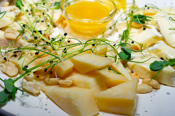 Variety of fresh cheeses served with honey and sprouts on a platter Savory vegetable pie served with fresh garnishes on a white plate