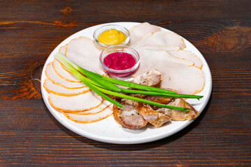 Assorted cold cuts presented on a white plate with dipping sauces Savory vegetable pie served with fresh garnishes on a white plate