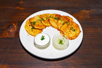Savory pancakes served with creamy dipping sauces on a rustic wooden table Savory vegetable pie served with fresh garnishes on a white plate