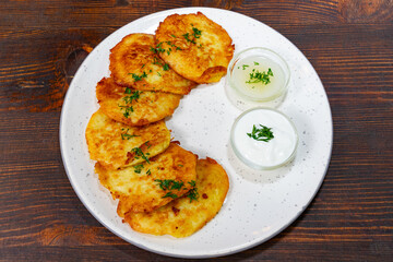 Crispy potato pancakes served with creamy dipping sauce on wooden table Savory vegetable pie served with fresh garnishes on a white plate